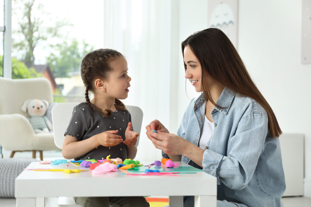 smiling mother and her daughter sculpting with play dough at tab