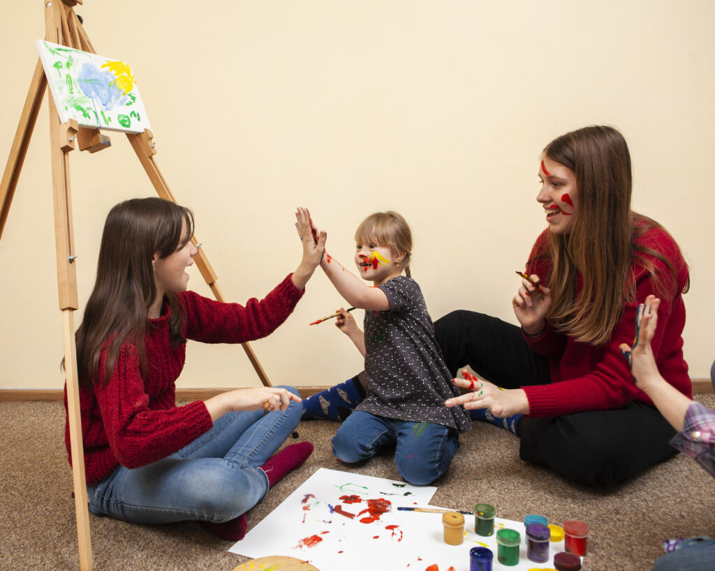 girl with down syndrome high fiving while painting