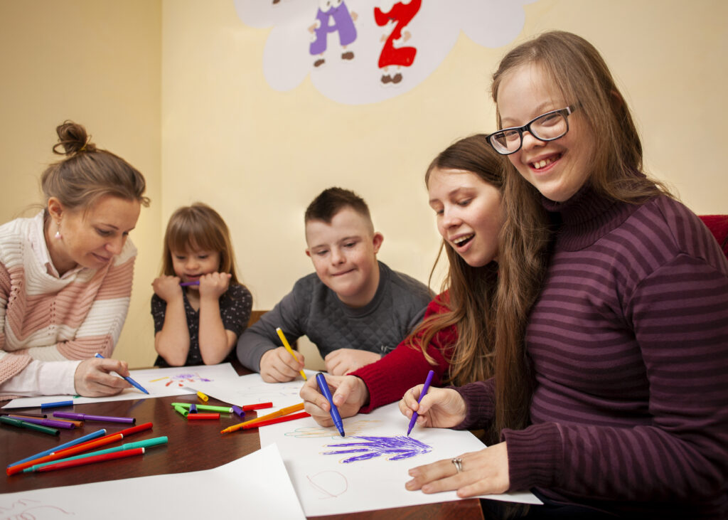 happy girl with down syndrome posing while drawing