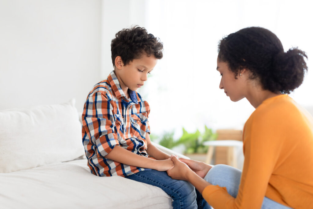 mommy comforting distressed son indoors, holding hands in deep conversation