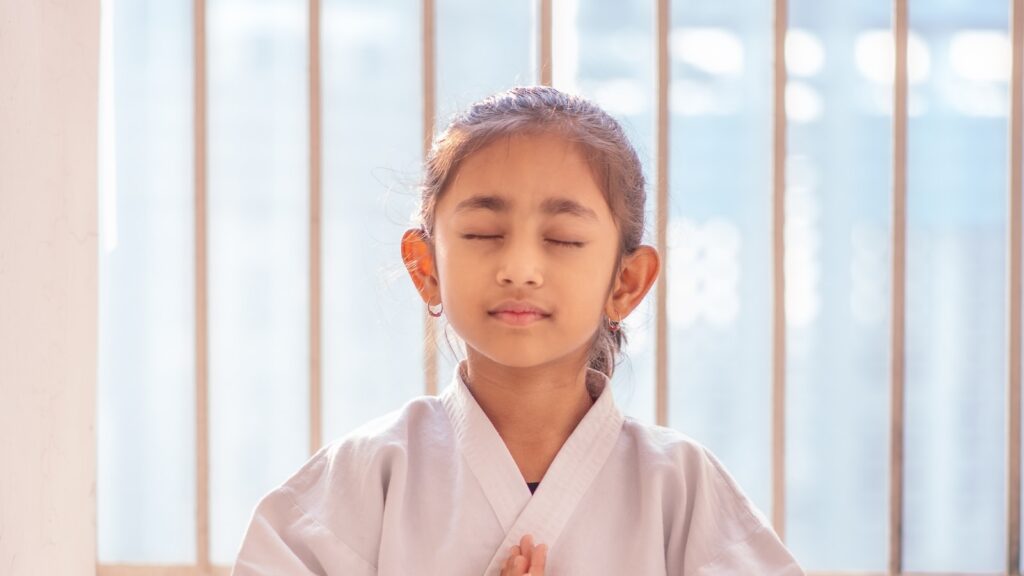 Child sitting cross-legged with eyes closed practising mindfulness for special needs children in Bangalore
